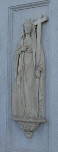 Stone carving of a woman in robes holding a large cross.