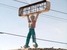 Statue of a guy in a turban atop a carpet store; store name is missing from sign.