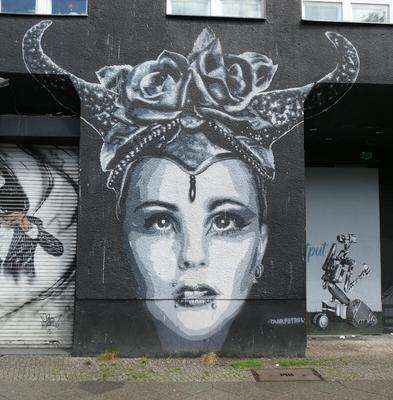 Woman with jewel on forehead, wearing a headdress with horns; there are roses in the center