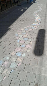 Pavement bricks colored with various colors of chalk. The pattern is a snake-like curve
