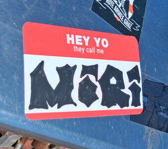 Name sticker with text: HEY YO they call me; name MiRi is written on sticker in black marker