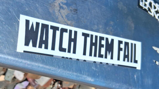 Sticker with black text on white background: WATCH THEM FAIL