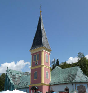 Spire of rose-colored church. Clock face is beneath the spire.