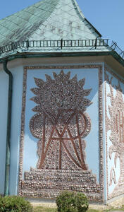 Mosaic of rounded rocks. Background is a sun shape. Atop it, overlaid letters.