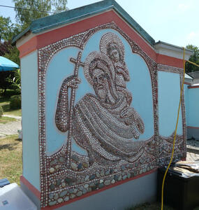 Person with halo carrying cross. On his back, a small figure who also has a halo.