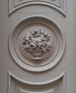 Gray-painted door with circular decoration of a vase of flowers.