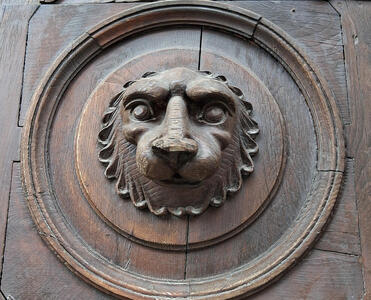 Brown wooden door with relief carving of bear’s head