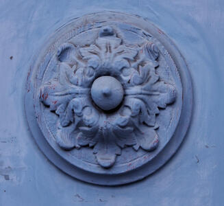 Relief carving of round symmetric flower-shaped design on light blue painted wood
