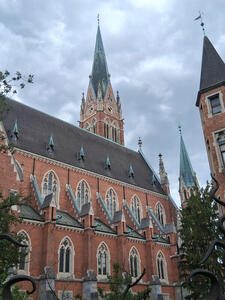 Exterior red brick church; spire with clock towre in background