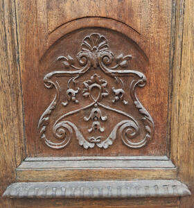 Brown wooden door with relief carving that looks somewhat like a coat of arms