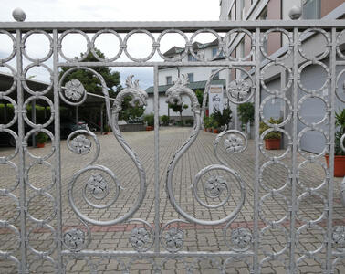 Silver colored metal gate with decoration in form of dragon headed snake with curled tail