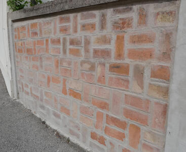 Brick wall with bricks of various shades of orange and brown.