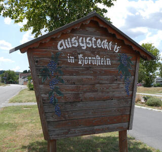 Wooden sign with text aus’gsteckt is’ in Hornstein (last two words in Fraktur)
