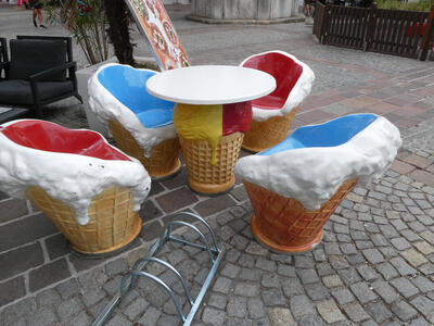 Chairs in shape of half-eaten ice cream cone with ice cream dripping down the sites. They are around a table that looks like an ice cream cone with a scoop of yellow and a scoop of red ice cream.
