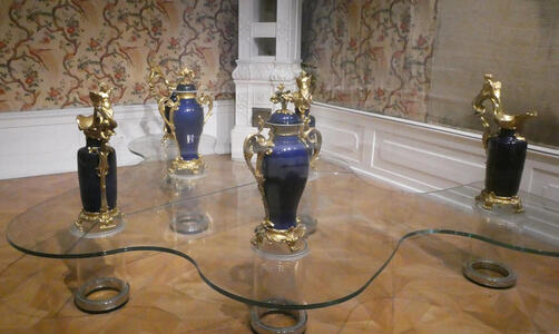 Several blue and several black vases with gold-decorated lids.