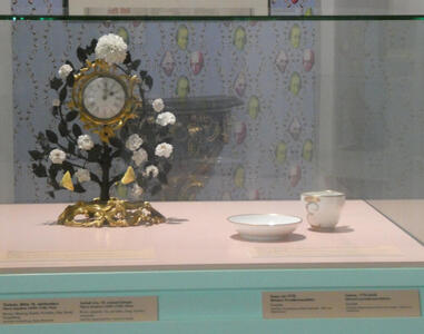At left, clock with floral decoration. At right, a cup and saucer