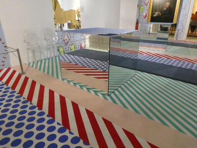 Mirrored cube reflecting wallpaper and carpeting.
