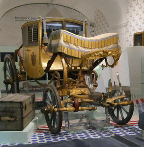 Gold-painted horse-drawn carriage with blue and gold canopy in driver’s area.