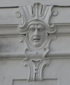 Relief carving of what looks like a jester with a neutral expression