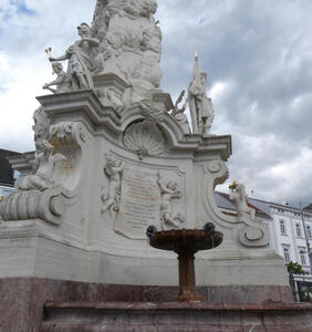 Curved base of Pestsäule with fountain in the curved area.