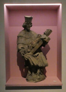 Stone statue of cleric holding a crucifix cradled in his arms