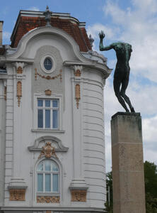 At left, an old, elegant building. At right, what appears to be a headless man on a column
