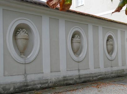 Wall with large oval niches; a carved urn is in each niche.