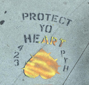 Stenciled PROTECT YO HEART, with ART in gold color, and an upside down gold colored heart beneath the words
