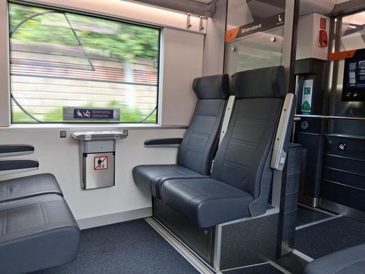 Interior of train showing shiny black seats, bright lighting
