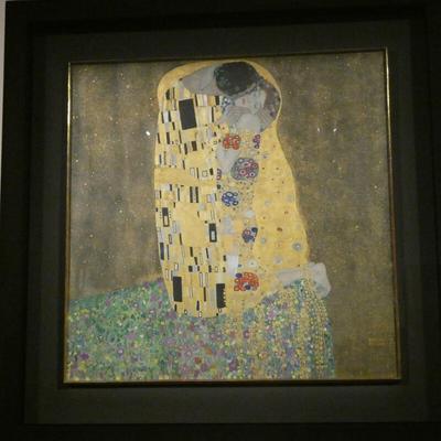 A man kissing a woman. They are wearing yellow abstract-patterned robes.