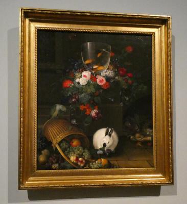 Still life with flowers at top of painting and fruit basket at bottom. A white bunny with black ears and nose is nibbling at some fruit.