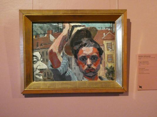 Self-portrait of artist wearing blue striped shirt with sleeves rolled up. He is lifting a Panama hat above his head.