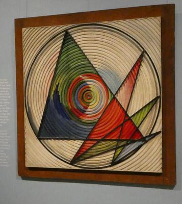 Abstract painting with concentric circles. Inside the circle are inscribed several triangles of varying sizes and colors.