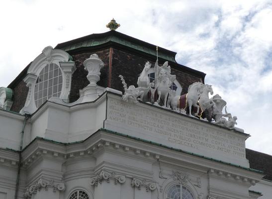 Sculpture atop buildling of man on horseback and several horses around him