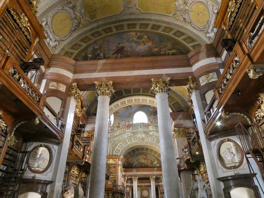 White columns with gold tops supporting a wooden beam. Atop it, a semicircular fresco