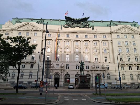 Large government building with eagle sculpture on top. In front, statue of man on horseback.
