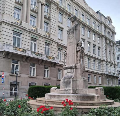 Column with bust of man on top. At base, red flowers