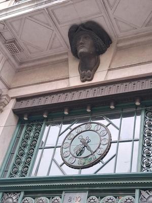 Bust of man above a clock embedded in a glass pane above a door