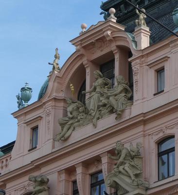 Pink building; in a niche at top, three seated women