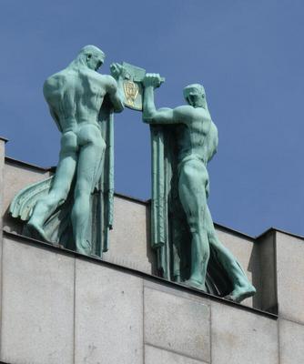 two bronze sculpture men supporting a plaque between them
