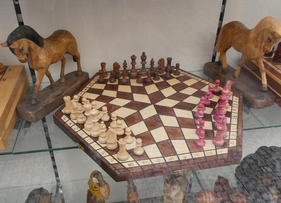 Pentagonal chess board allowing three players to play simultaneously. Chess pieces are white, brown, and red
