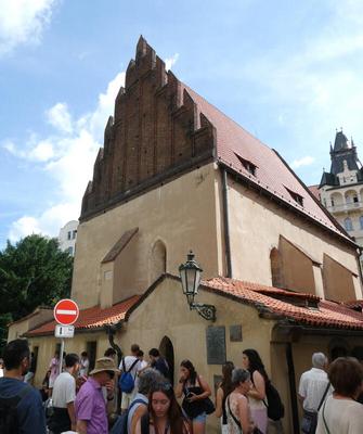 Exterior of Jewish synagogue with peaked dark brown roof and beige stone walls.