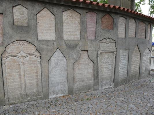 Wall with examples of headstones of various shapes )trapezoidal, house shaped, rectangular, etc.