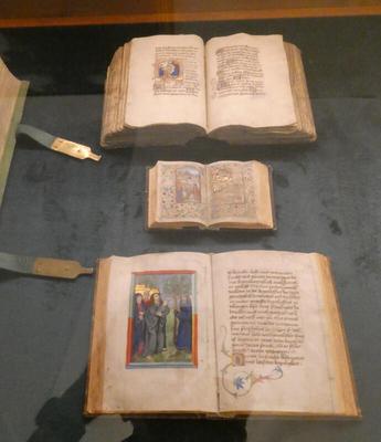 Three illuminated manuscripts; the one in the center is very small compared to the other two.
