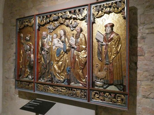 Painted wood carving of religious figures. In middle panel is Mary with baby Jesus.