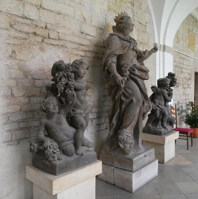 In center, statue of a woman wearing a gold crown. On either side, statues of cherubim