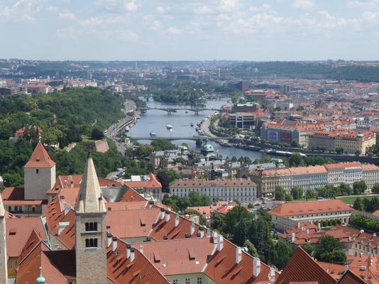 View of city showing river with two bridges in center of photo. To left, tree-covered area. To right, buildings.