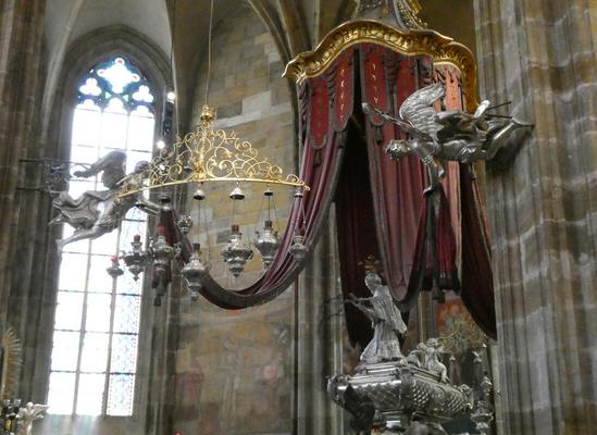 Drapery, with an angel statue attached to the wall holding one end of the drape so it does not hang loose.
