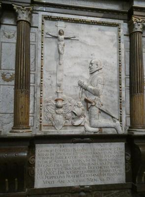 Relief carving of man with sheathed sword at his side. He is on his knees praying to a crucifix