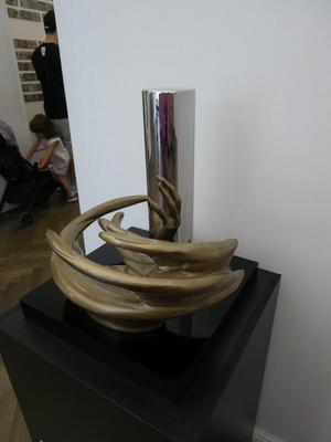 Bronze sculpture that looks like twisted tubes. When viewed in a cylindrical mirror, it is a hand.